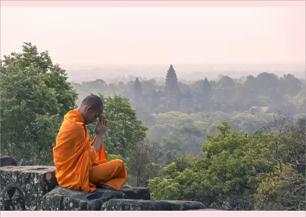 Cambodia, Siem Reap, Angkor Wat complex. Monk meditating with Angor wat temple in the background