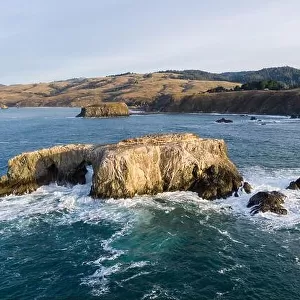 The Pacific Ocean washes against a sea stack off the northern California Sonoma coast. This region is often covered by a thick marine layer of mist