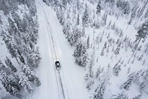 Chilly Collection: Aerial shot of a car crossing the boreal forest covered with snow, Akaslompolo, Finnish Lapalnd