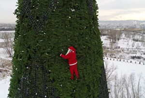 Aerial Views Fine Art Print Collection: A climber dressed as Santa Claus decorates a Christmas tree in Krasnoyarsk