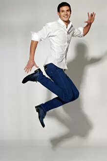 Attire Collection: Young man in white shirt and blue jeans jumping