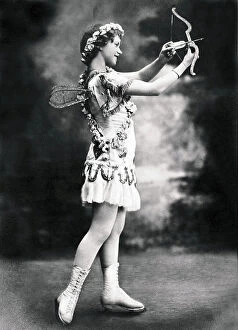 Red Arrows Fine Art Print Collection: Young girl in Cupid's costume with ice skates, and a bow with an arrow. Red tone photography, 1915