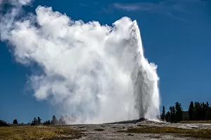 Hydrothermal Collection: Old Faithful erupting into the air against a blue sky, Yellowstone National Park, Wyoming, USA