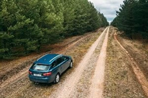 Compact Collection: Lada Vesta Parked On Roadside. Country Road Through Forest